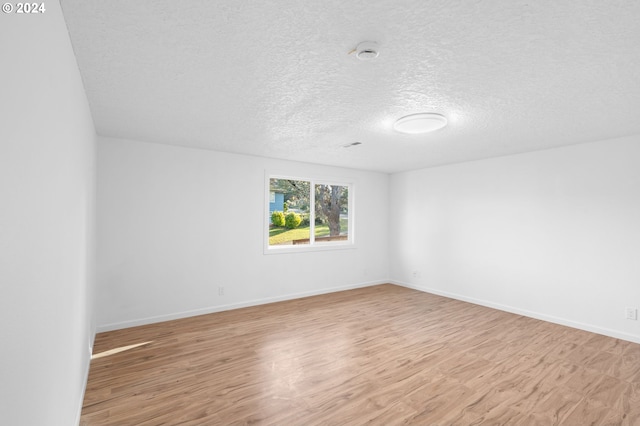 unfurnished room with light wood-type flooring and a textured ceiling