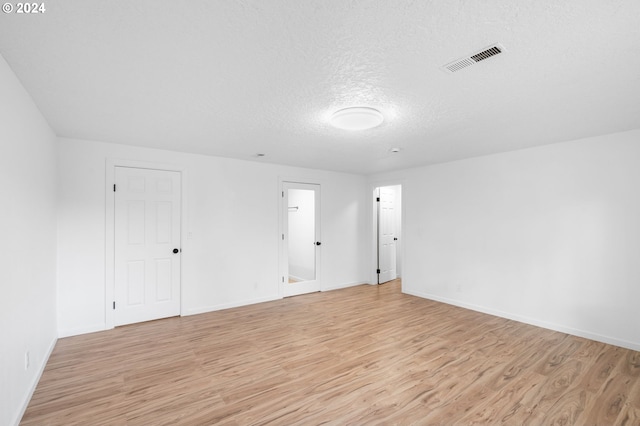 unfurnished room featuring light hardwood / wood-style floors and a textured ceiling