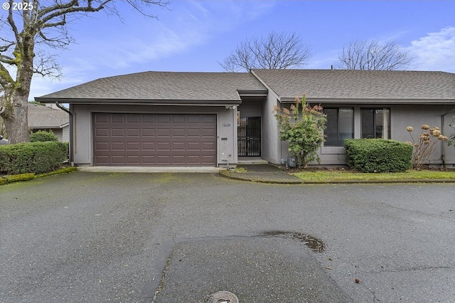 view of front of house with an attached garage, stucco siding, aphalt driveway, and roof with shingles