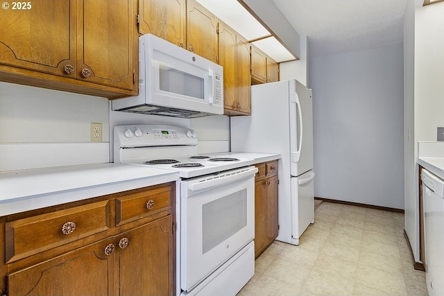 kitchen with white appliances, baseboards, light countertops, brown cabinets, and light floors