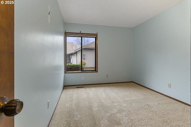 carpeted spare room featuring a textured ceiling and baseboards