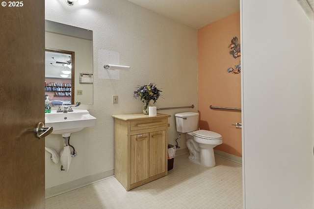 bathroom featuring baseboards, a sink, and toilet