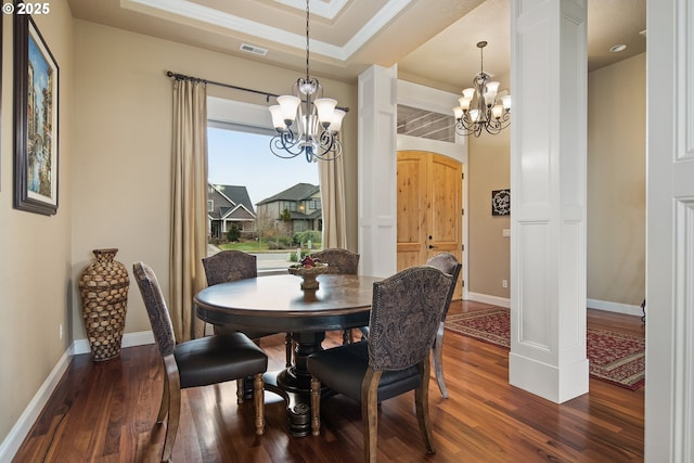 dining area featuring dark wood-style floors, baseboards, a raised ceiling, and a notable chandelier