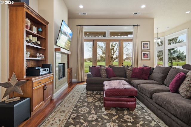 living area featuring dark wood-style floors, a tiled fireplace, visible vents, and a wealth of natural light