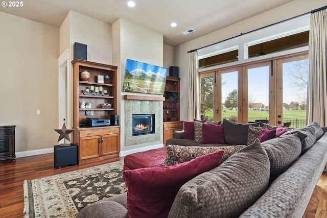 living area featuring baseboards, visible vents, dark wood finished floors, a glass covered fireplace, and recessed lighting