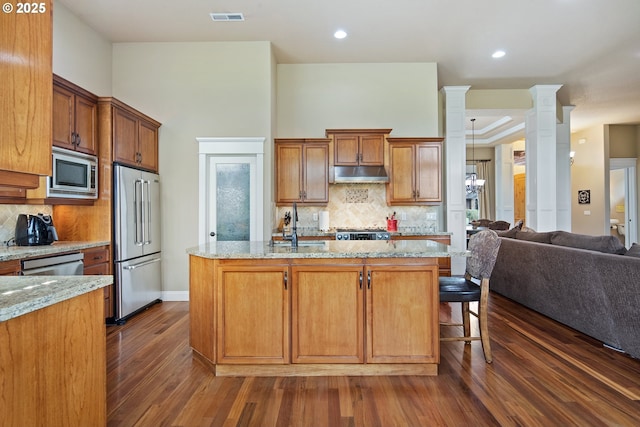 kitchen with decorative columns, visible vents, open floor plan, stainless steel appliances, and under cabinet range hood