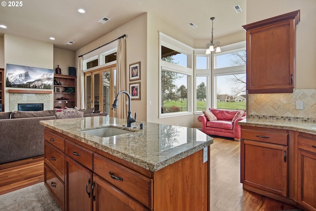 kitchen with light wood-type flooring, open floor plan, visible vents, and a sink