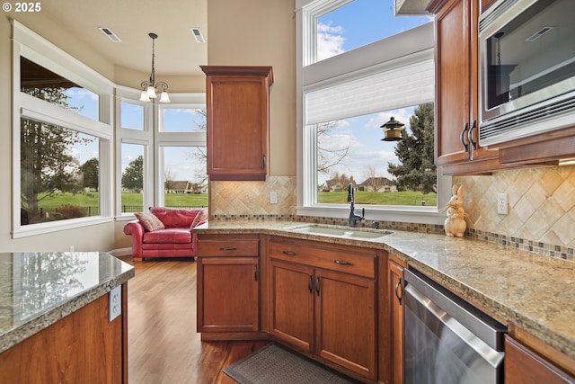 kitchen featuring pendant lighting, visible vents, appliances with stainless steel finishes, a sink, and wood finished floors