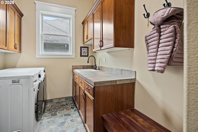 washroom featuring cabinet space, a sink, and independent washer and dryer