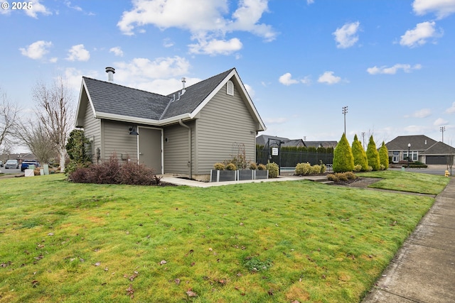 view of side of home featuring a lawn and roof with shingles