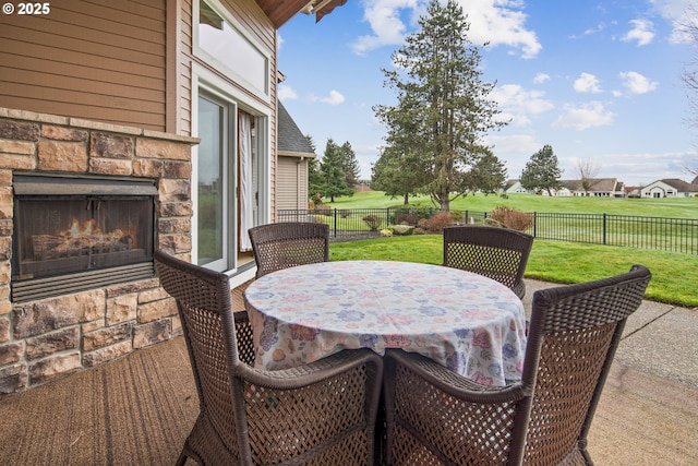 view of patio with outdoor dining space, an outdoor stone fireplace, and a fenced backyard