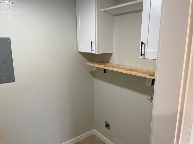 laundry area featuring cabinets, electric panel, wood-type flooring, and electric dryer hookup