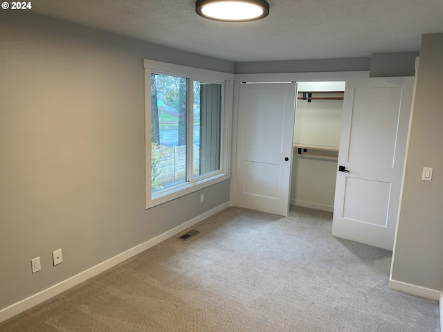 unfurnished bedroom featuring a closet and light carpet