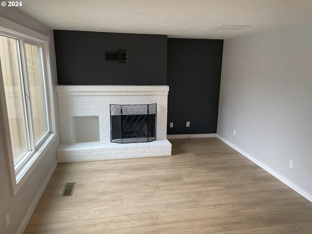 unfurnished living room with a fireplace and light wood-type flooring