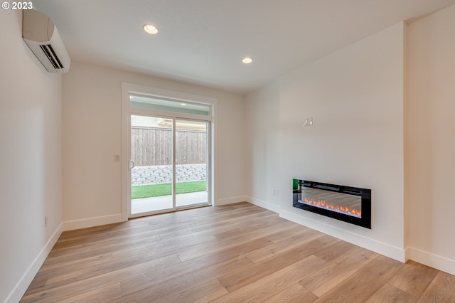 unfurnished living room featuring light hardwood / wood-style floors and a wall mounted air conditioner