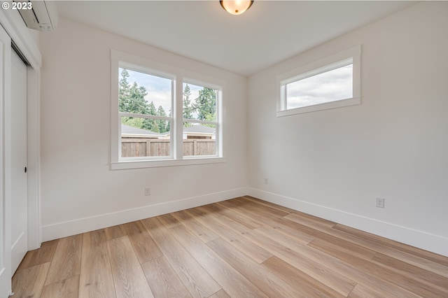 spare room featuring light hardwood / wood-style flooring and a wall mounted AC