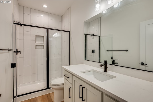 bathroom featuring a shower with shower door, vanity, toilet, and hardwood / wood-style flooring