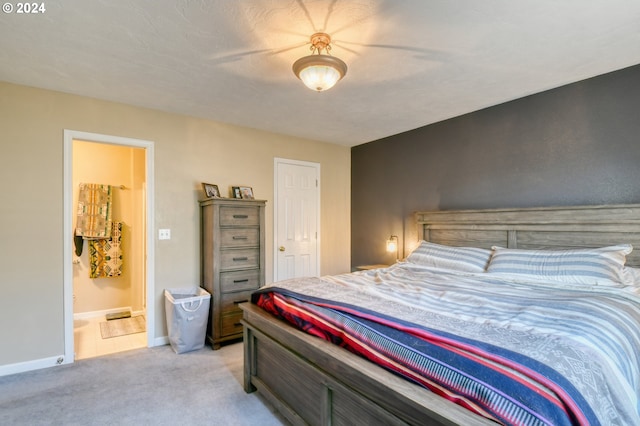 bedroom featuring ceiling fan, ensuite bath, and light carpet