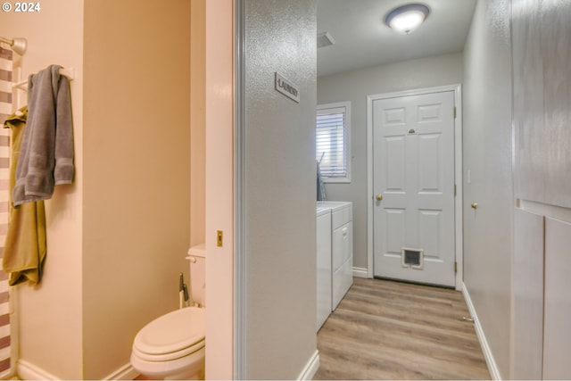 bathroom with hardwood / wood-style flooring, toilet, and independent washer and dryer