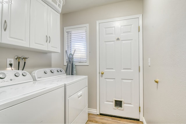 laundry area with cabinets, light hardwood / wood-style flooring, and washer and clothes dryer