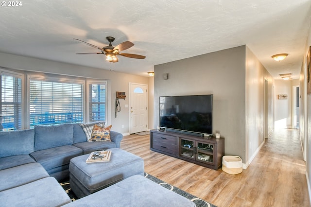 living room with a textured ceiling, ceiling fan, and light hardwood / wood-style flooring