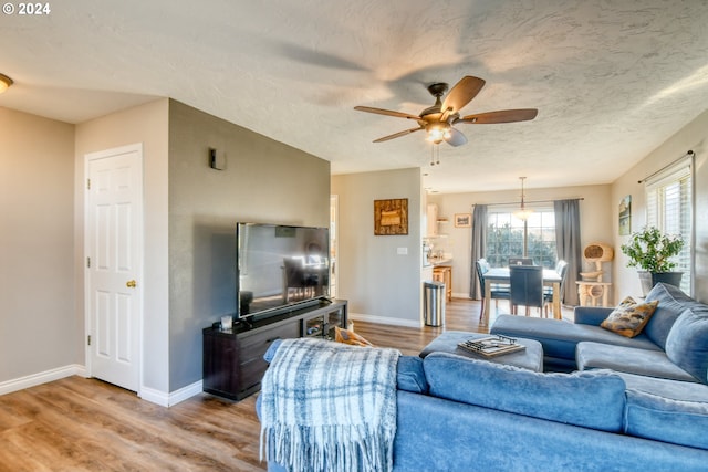 living room featuring light wood-type flooring, a textured ceiling, and ceiling fan