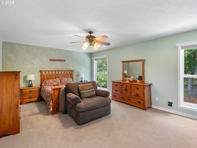 bedroom with ceiling fan, light colored carpet, and a textured ceiling