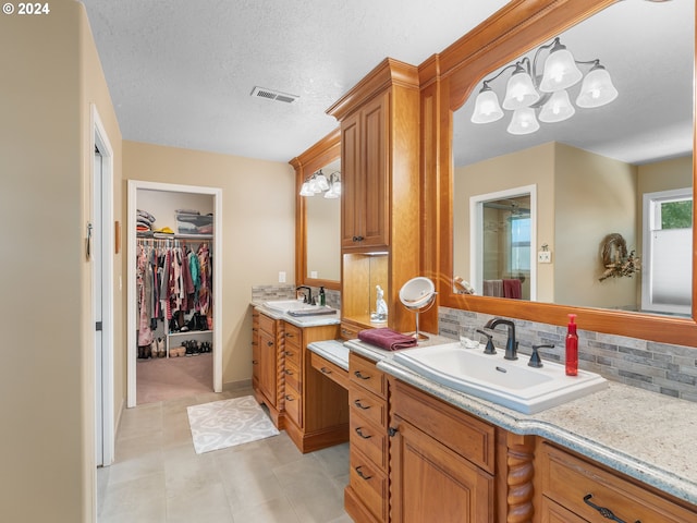 bathroom with tile patterned floors, decorative backsplash, a textured ceiling, and vanity