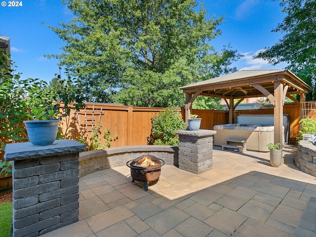 view of patio featuring a fire pit, a hot tub, and a gazebo