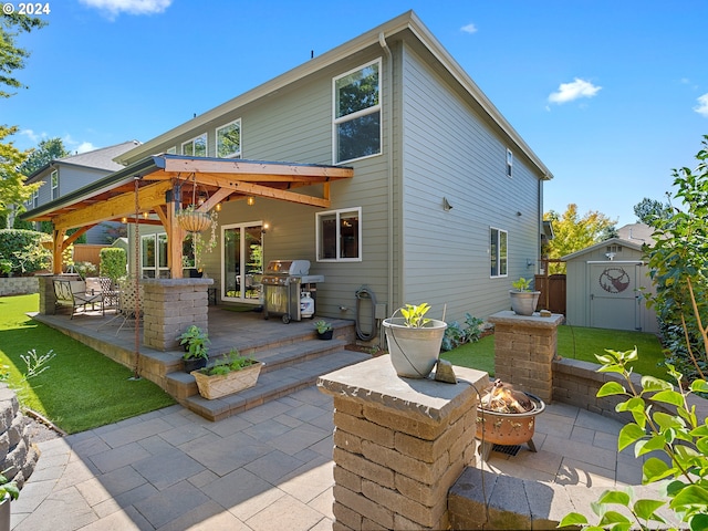 back of house with a gazebo, a patio area, a fire pit, and a storage shed