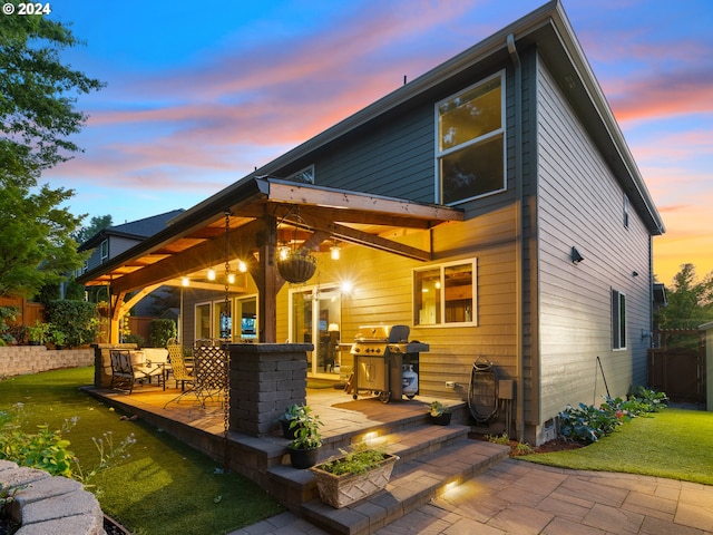 back house at dusk featuring a yard and a patio