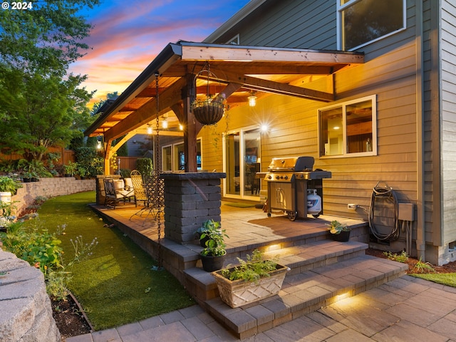 patio terrace at dusk featuring a yard and grilling area