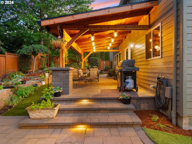 patio terrace at dusk featuring ceiling fan and area for grilling