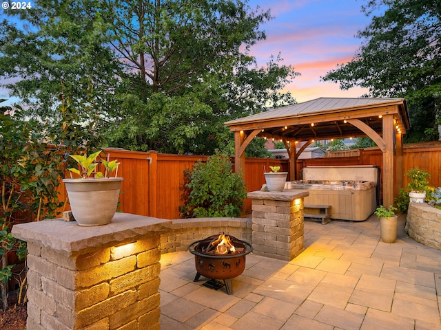 patio terrace at dusk featuring a fire pit and a gazebo