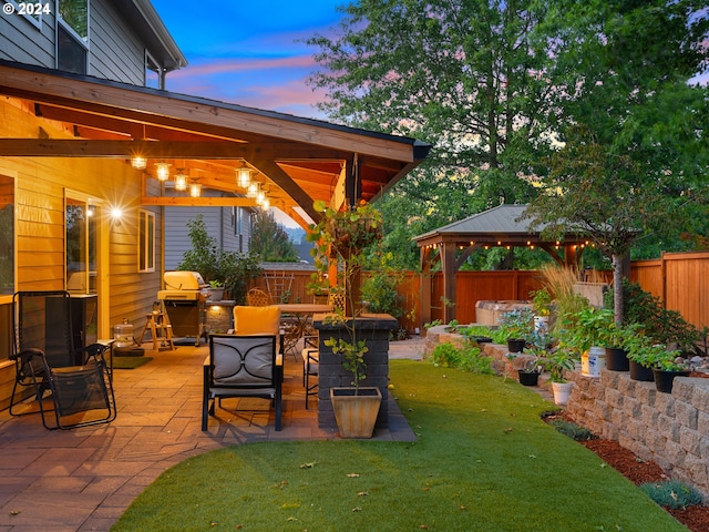 yard at dusk featuring a patio area and a gazebo