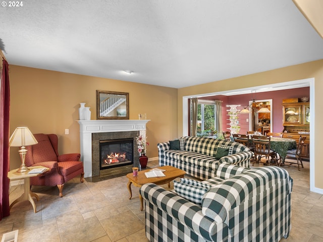 living room featuring a tiled fireplace and a textured ceiling