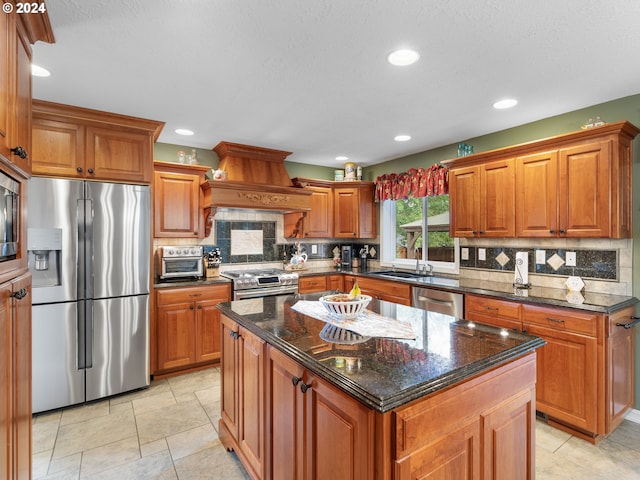 kitchen featuring custom range hood, a center island, stainless steel appliances, decorative backsplash, and dark stone countertops