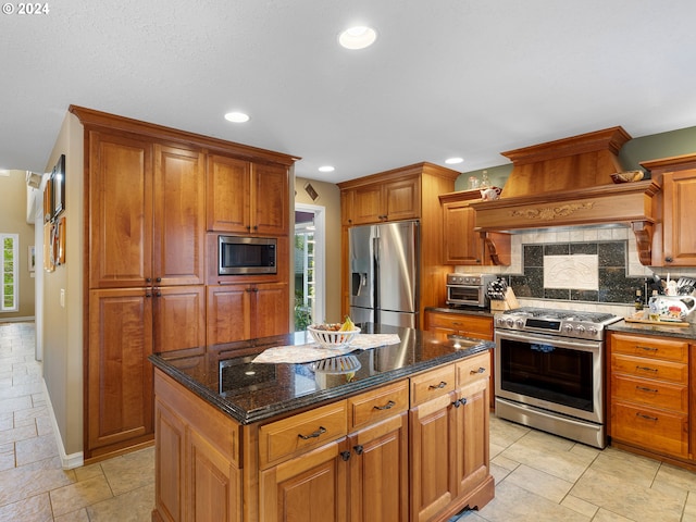 kitchen with premium range hood, tasteful backsplash, a center island, stainless steel appliances, and dark stone counters