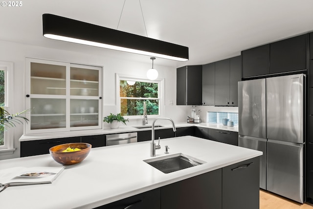 kitchen with appliances with stainless steel finishes, light hardwood / wood-style flooring, pendant lighting, and sink