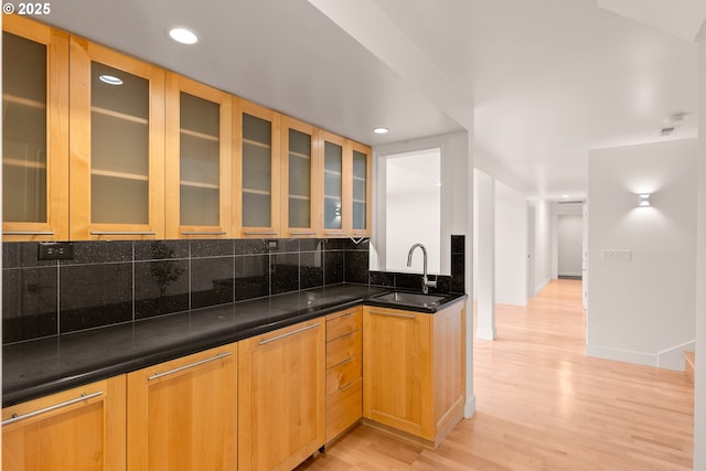 kitchen with dark stone counters, light hardwood / wood-style flooring, decorative backsplash, and sink