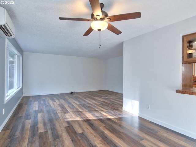 empty room with a wall mounted AC, a textured ceiling, and dark hardwood / wood-style flooring