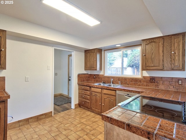 kitchen featuring sink, tile countertops, stovetop, and stainless steel dishwasher