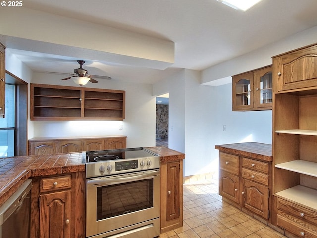 kitchen with ceiling fan, dishwashing machine, tile counters, and electric stove