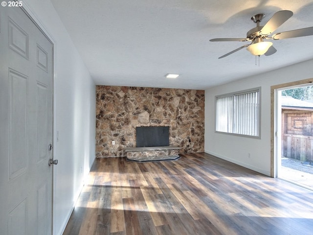 unfurnished living room featuring a fireplace, dark hardwood / wood-style floors, and ceiling fan