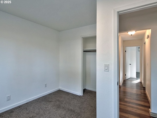 unfurnished bedroom with dark carpet and a closet