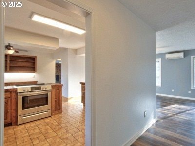 kitchen with ceiling fan, electric range, and a wall mounted AC