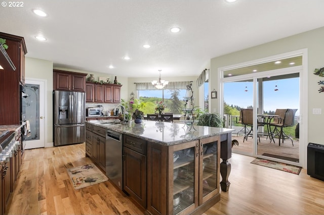 kitchen featuring an inviting chandelier, stainless steel appliances, pendant lighting, and light wood-type flooring