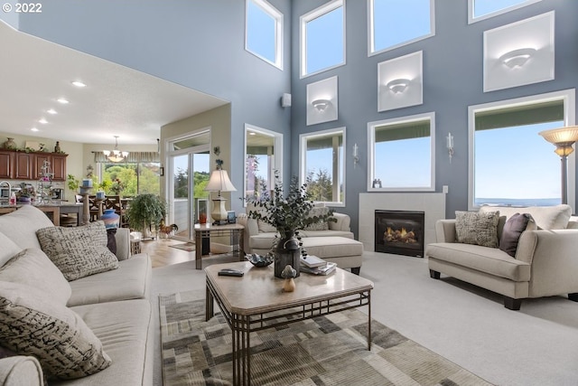 carpeted living room featuring a high ceiling and a notable chandelier