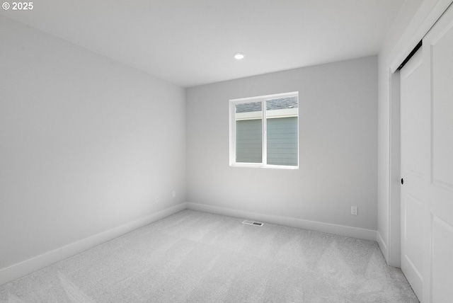 unfurnished bedroom with light colored carpet, baseboards, recessed lighting, and a closet