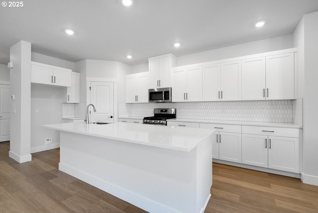 kitchen featuring wood finished floors, white cabinetry, stainless steel appliances, and a sink